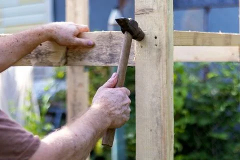 Close-up of hands of man with vitiligo using hammer to assemble wooden fram.. Stock Photos