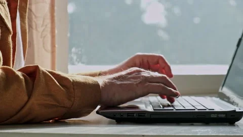 Close-up of the hands of a man working at a laptop near the window. slow motion. Video stock 184209648