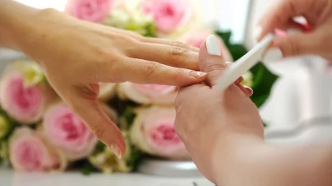 Close-up of the hands of a manicurist filing the nails of a young woman Stock Footage 112013096