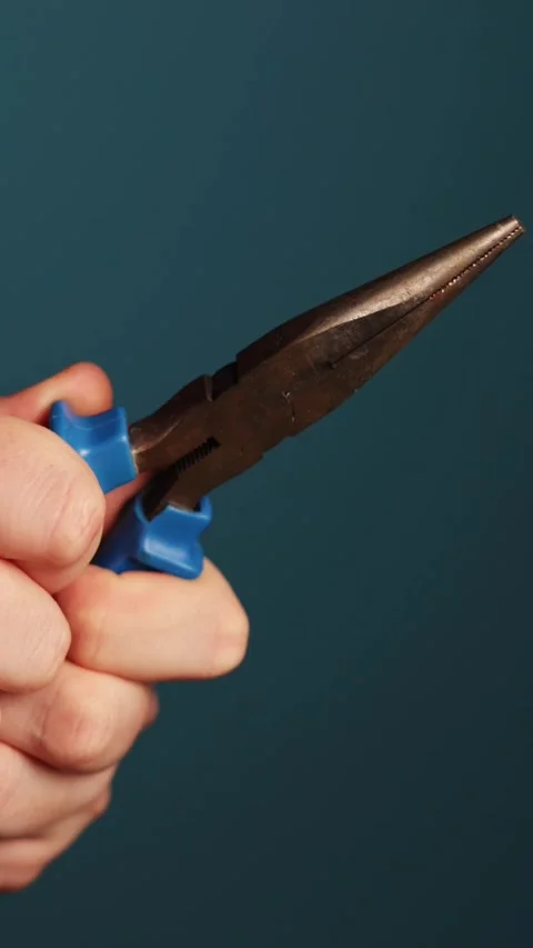 Close-up of hands manipulating needle-nose pliers against a blue background Video stock 343838069