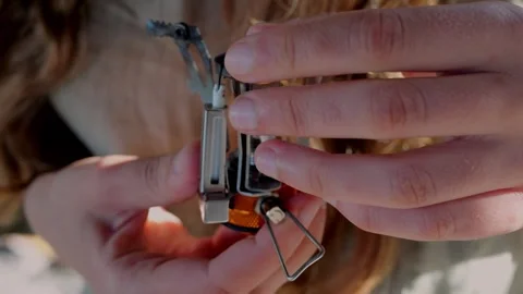 Close-up of hands manually unfolding metal pot supports on compact... Stock Footage 322811564