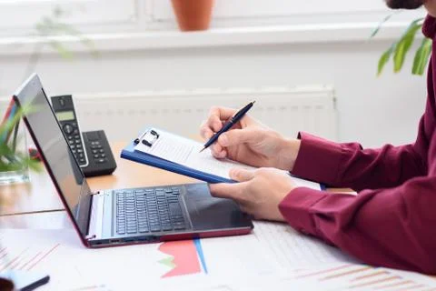 Close-up of hands of men making notes in a notebook against the background of Stock Photos