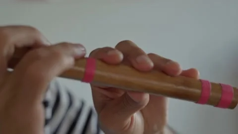 Close-up of the hands of men playing a wooden flute with pink lines against a Stock Footage 196868697