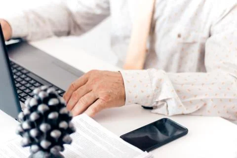 Close-up of hands middle-aged man in white shirt and yellow tie typing on key Stock Photos