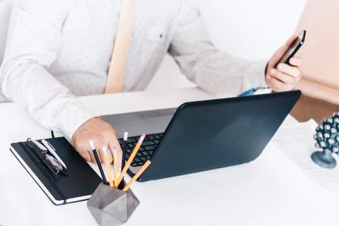 Close-up of hands middle-aged man in white shirt and yellow tie typing on key Stock Photos