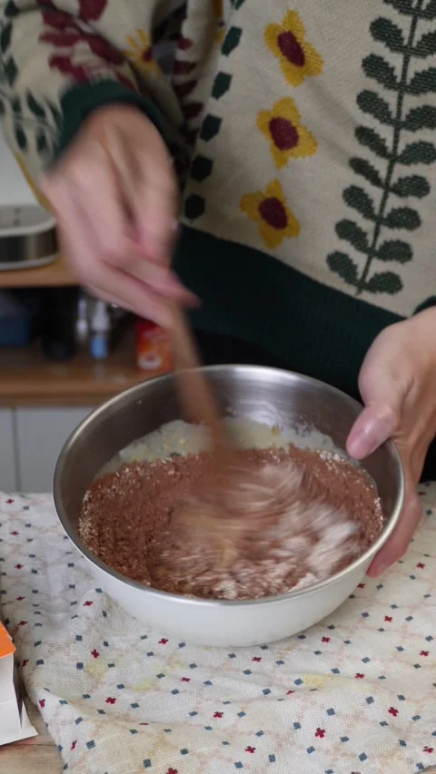 Close-up of Hands Mixing Chocolate Batter in Bowl with Spoon Stock Footage 340860782