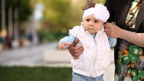 Close-up a hands of mother holding cute little laughing girl in the park. Stock Footage 75443124