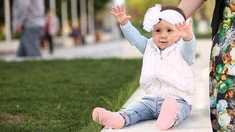 Close-up a hands of mother holding cute little laughing girl in the park. Stock Footage 75443165