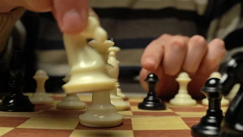 Close-up of hands moving chess pieces on a wooden board, showcasing strategic Stock Footage 332866807