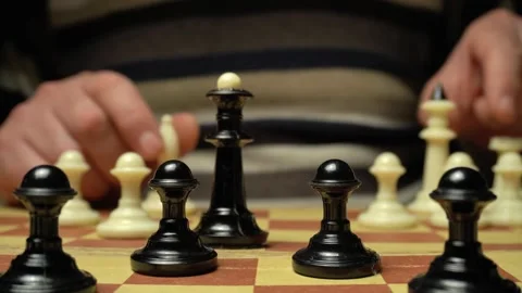 Close-up of hands moving chess pieces on a wooden board, black and white pawns Stock Footage 333146530