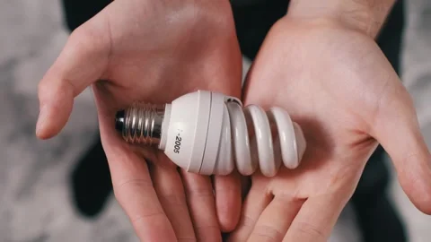 Close Up Hands Offering Spiral CFL Energy Saving Bulb Stock Footage 305856521