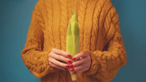 Close-up hands in ohra sweater cleaned corn on blue background. Stock-Footage 136856472