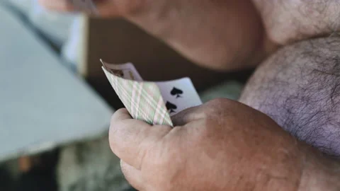 Close-up of the hands of an old man with bare torso playing cards in the garden Stock-Footage 134392841
