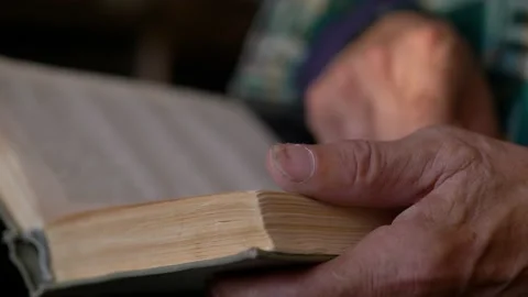 Close-up in the hands of an old man an old open book, selective focus, shallow d 스톡 동영상 219225180