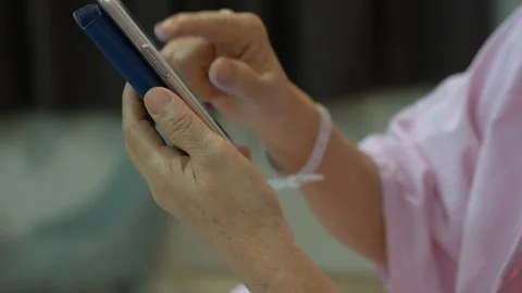 Close up hands of old woman using smartphone in hospital room, entertainment  Stock Footage 107883039