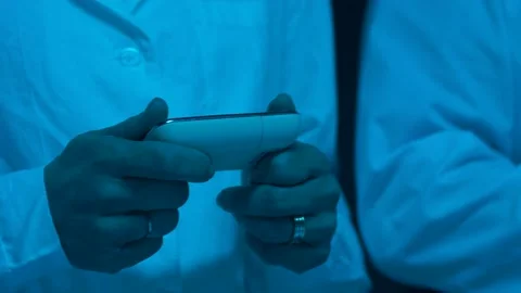 Close-up of hands of one of the doctors in a white coat holding a remote control Stock Footage 143379780