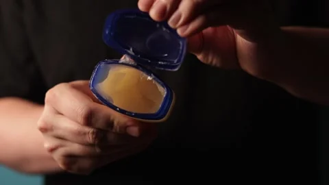 Close-up of hands opening and closing a petroleum jelly container Stockbeeldmateriaal 340268516