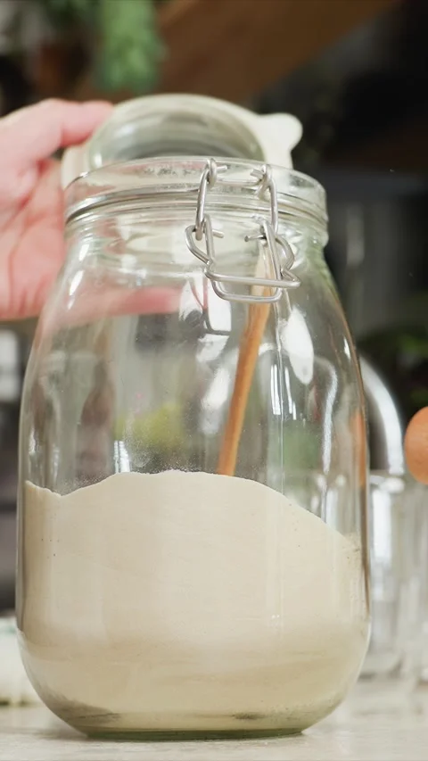 Close up of hands opening closing glass jars with flour stirring powder in Video stock 344426402