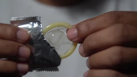 Close up of hands opening a condom wrapper Stock Footage 314385005