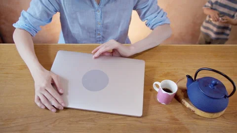 Close-up hands opening laptop at table home, little child playing on background Stock Footage 134577302