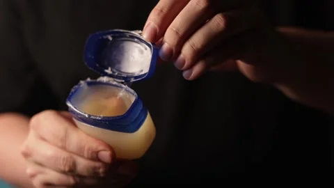 Close-up of hands opening a small jar of petroleum jelly for skin care Stock Footage 340267444