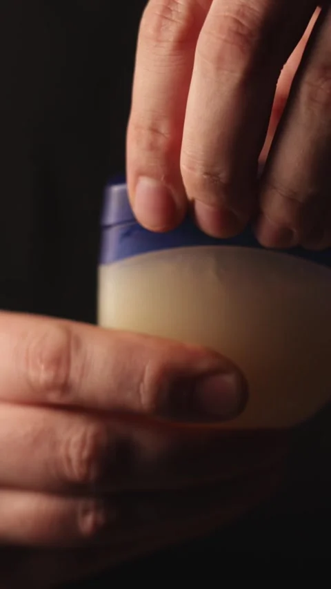 Close-up of hands opening a small jar of petroleum jelly for skincare Stock-Footage 343838051