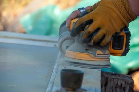 A close-up of hands operating a palm sander on a wooden door Stock Photos