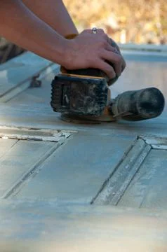 A close-up of hands operating a palm sander on wood Stock Photos