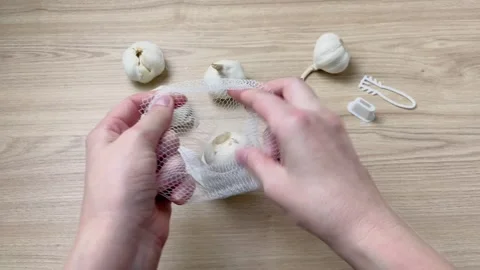 Close-up of hands packing garlic in a plastic net. Stock Footage 336354136