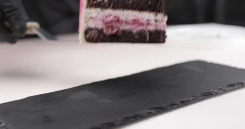 A close-up of the hands of a pastry chef placing a piece of blueberry-garnished Vídeo Stock 165455531