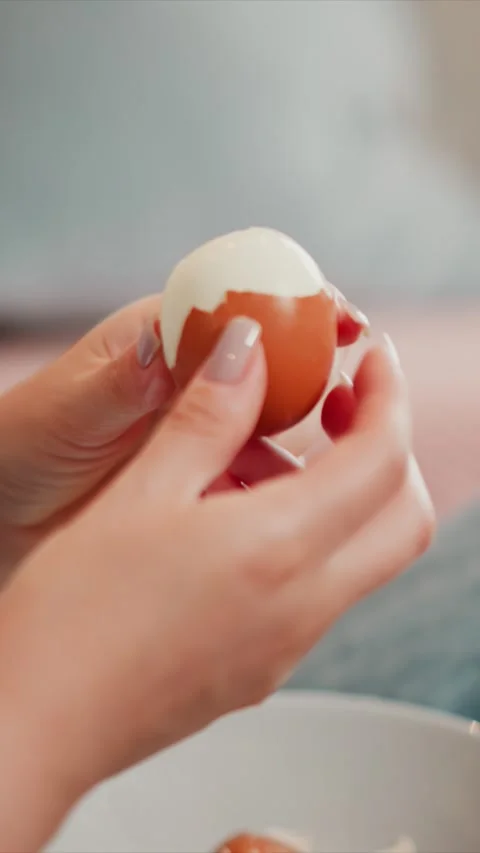 Close up of hands peeling fresh brown egg revealing smooth white interior with Stock Footage 346796269