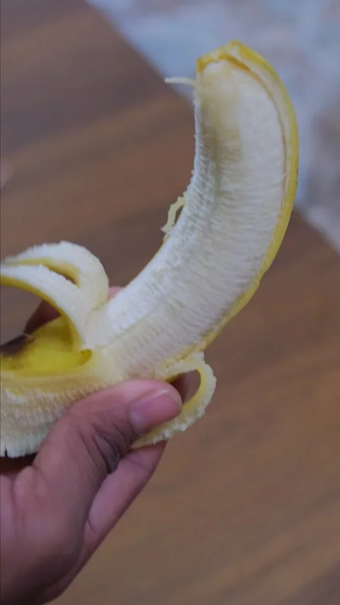 Close up of hands peeling a fresh yellow banana in a kitchen Video stock 333203301