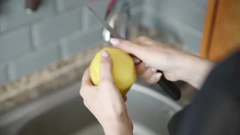Close up hands peeling fresh yellow potato over kitchen sink with grey tile.. Stock Footage 333699395