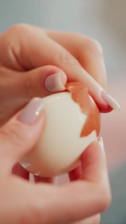 Close up of hands peeling hard boiled egg revealing smooth white surface Stock Footage 345982665
