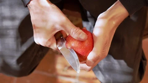 Close-up of hands peeling a red apple with a sharp knife, precision knife work Stock Footage 303889811