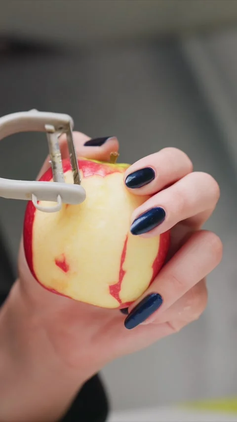 Close up of hands peeling red apple with white handled vegetable peeler Stock Footage 346796446