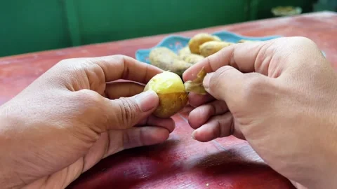Close up of hands peeling skin off boiled yellow potato Stock Footage 340050012