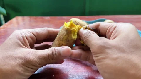 Close up of hands peeling skin off boiled yellow sweet potato Stock Footage 340050089