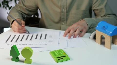 Close-up of hands performing calculations with a calculator while referencing Stock Footage 316458862