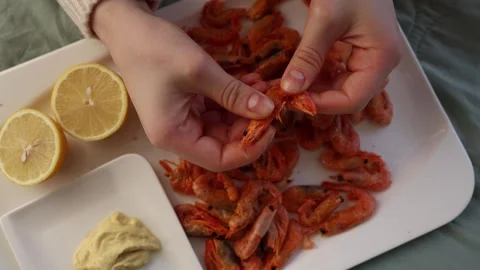 A close-up of hands picking dried shrimp from a plate, accompanied by fresh lemo Stock Footage 294705016