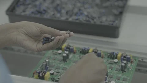 Close-up of hands placing capacitors on a PCB in a manufacturing plant Stock-Footage 327597330