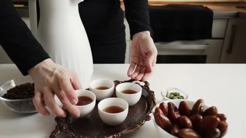 Close-up of hands placing a filled white finjan cup onto a copper tray with.. Stock Footage 332791584