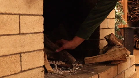 Close-up of hands placing firewood into a fireplace and lighting the fire. Cozy  Stock Footage 325955419