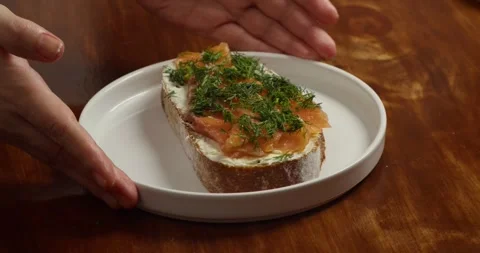 Close up of hands placing an open sandwich with salted fresh salmon and dill Stock Footage 335813172