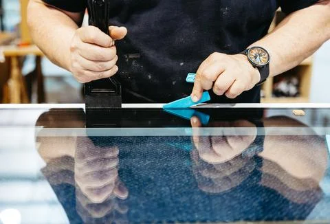 Close-up of hands placing suction cups on glass during window assembly Foto stock