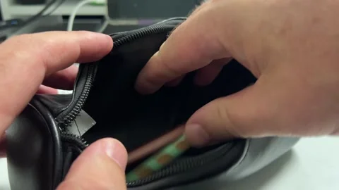 A close-up of hands placing two colored pencils into an open black zipper p.. Stock Footage 322982220