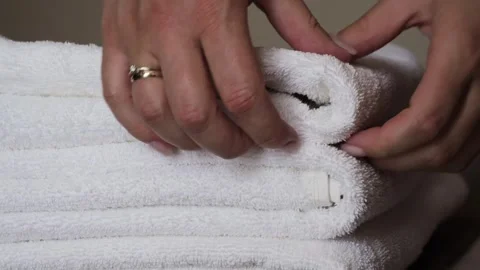 Close-up of hands placing white bath towels on the bed sheet. Concept of room Stock Footage 320558845