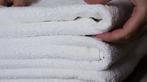 Close-up of hands placing white bath towels on the bed sheet. Concept of room Stock Footage 323442807