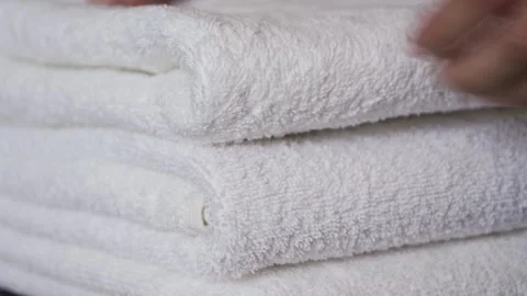 Close-up of hands placing white bath towels on the bed sheet. Concept of room Stock-Footage 330132568