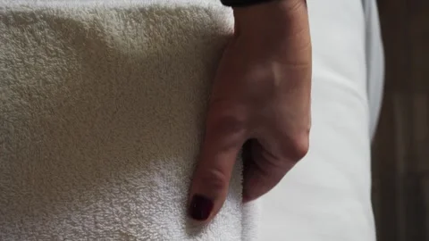 Close-up of hands placing white bath towels on the bed in the hotel room. Room Video stock 335807347